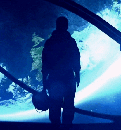 a silhouette of a person holding a helmet in front of an aquarium