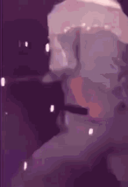 a person is dancing on a stage with a microphone in a dark room .