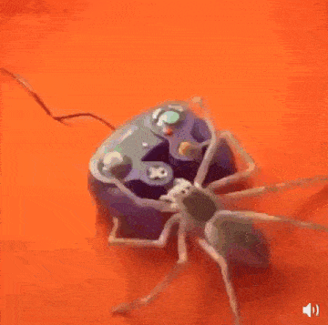 a spider is sitting on top of a video game controller on an orange surface .