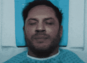 a man in a hospital gown is laying in a hospital bed with his eyes closed