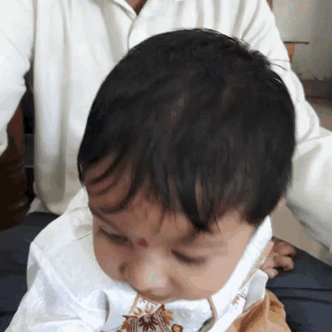 a baby with a red spot on his forehead is being held by a man