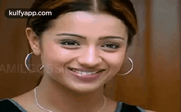 a woman wearing hoop earrings and a necklace is smiling for the camera .