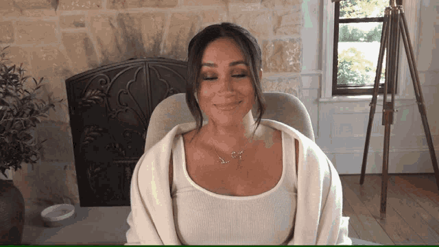 a woman wearing a white tank top and a necklace with the letter s on it
