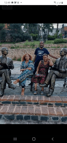 a group of people sitting on a bench with statues