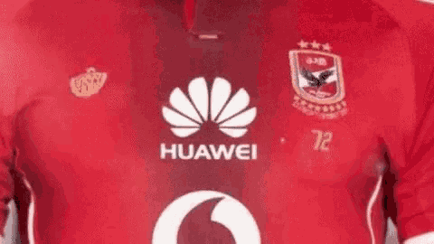 a close up of a person wearing a red huawei soccer jersey .