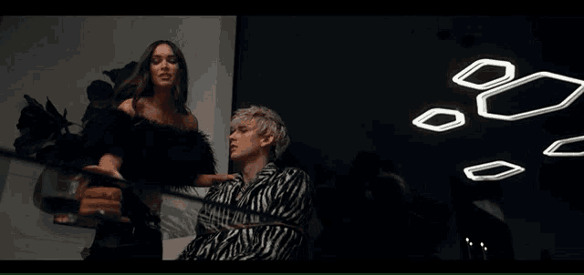 a man in a zebra print shirt is tied up by a woman in a black dress