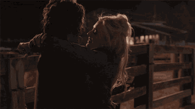 a man and a woman are kissing in front of a fence