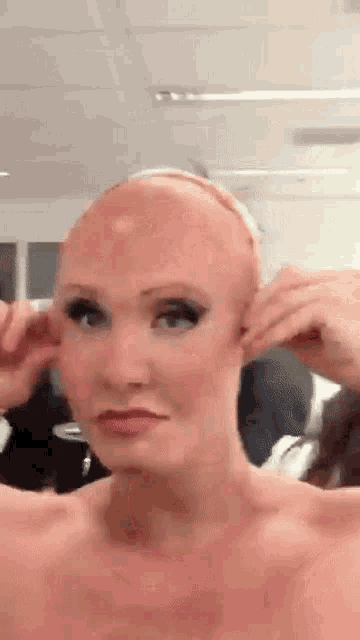 a woman with a wig on her head looks at herself in the mirror .