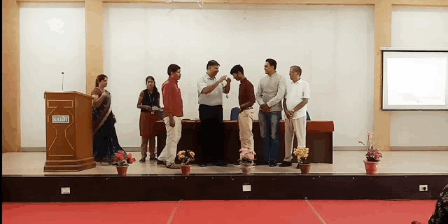 a group of people standing on a stage in front of a podium that says ' shree ' on it