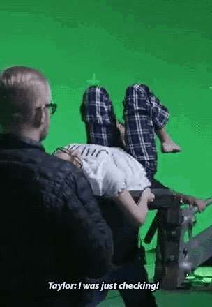 a man is sitting next to a woman who is laying on a green screen .