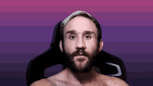 a shirtless man with a beard is sitting in a chair with a purple background