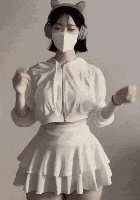 a woman wearing a white mask and headphones dancing