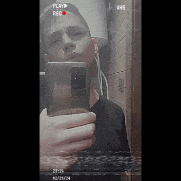 a young man is taking a selfie in front of a vhs tape player
