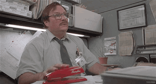 a man is using a stapler in his office cubicle .