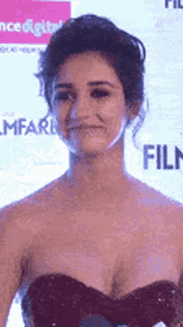 a woman in a strapless dress stands in front of a sign that says filmfare