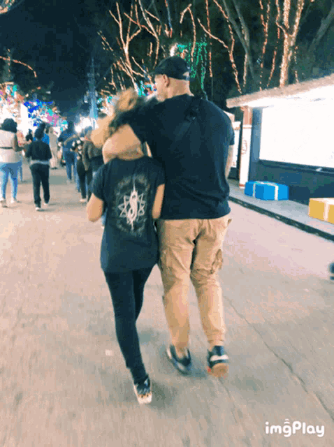 a man and a woman are walking down a street with a sign that says imgplay on the bottom right