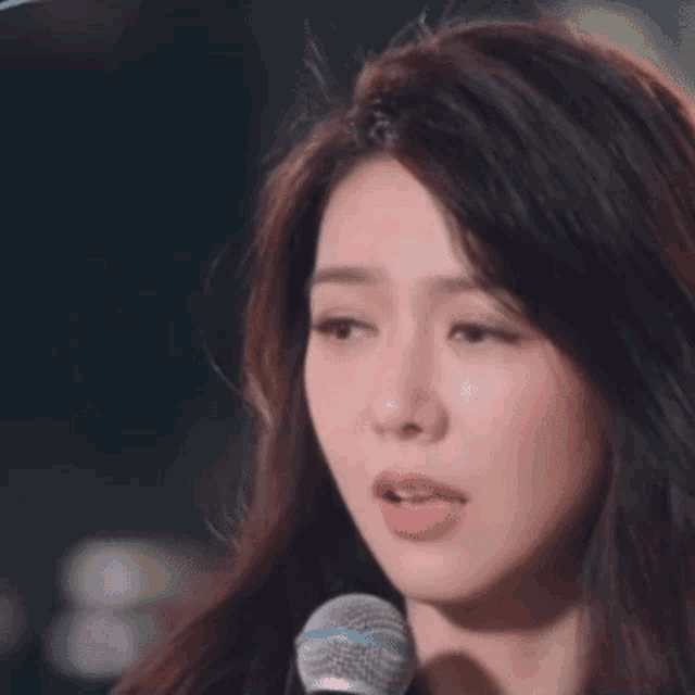 a woman is singing into a microphone and making a face