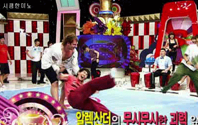 a man is wrestling another man on a stage with korean writing