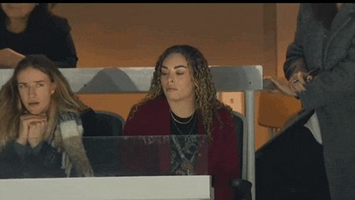 a woman sits with her eyes closed in a stadium
