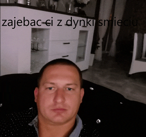 a man is sitting in front of a dresser with the words zajebac ci z dynki smieci