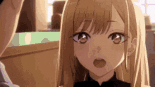 a close up of a blonde anime girl talking to a man in a room .