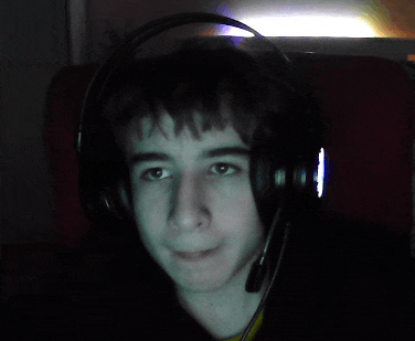 a young man wearing headphones and a microphone looks at the camera