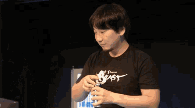 a man wearing headphones holds a can of red bull in front of another man