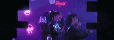 a group of girls are dancing in front of a neon sign that says " stay wild "