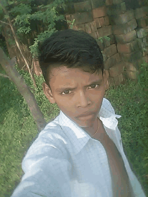 a young man taking a selfie with a brick wall behind him