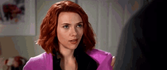a woman with red hair is wearing a purple sweater .