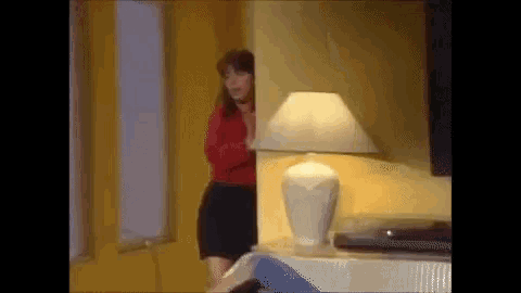 a woman peeking out from behind a lamp in a living room .