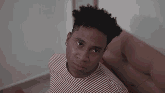 a man in a red and white striped shirt is sitting on a couch