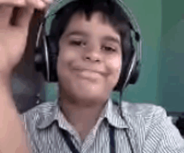 a young boy wearing headphones is smiling and holding a pen in his hand .