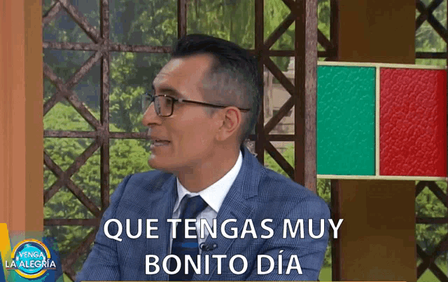 a man wearing glasses and a suit says que tengas muy bonito dia