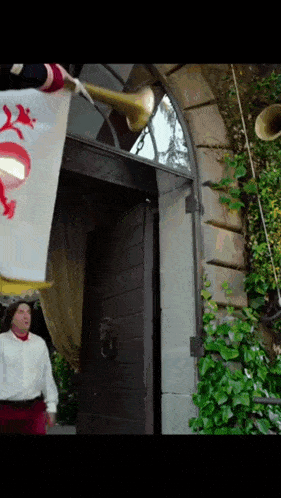 a man playing a trumpet in front of a door with a flag hanging from it