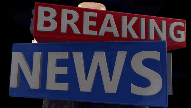 a man is holding a sign that says breaking news