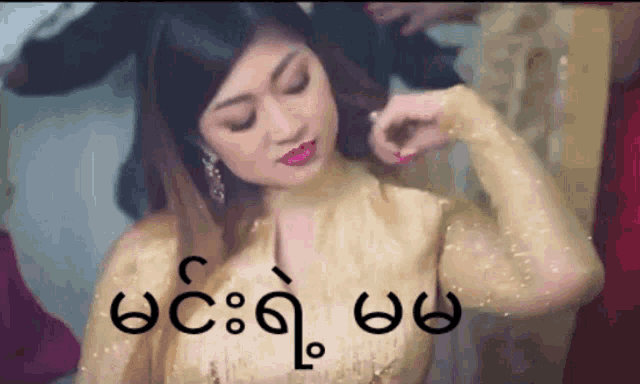 a woman in a gold dress has a foreign language written on her chest