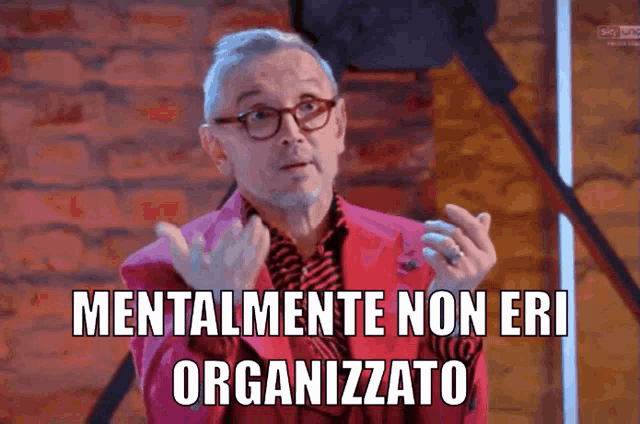 a man wearing glasses and a pink jacket has the words mentalmente non eri organizzato above him