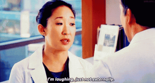 a woman in a white coat is laughing while talking to a man .