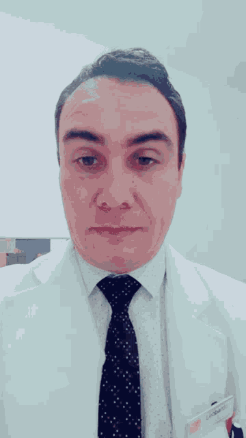 a man wearing a white coat and tie with a name tag that says leonardo