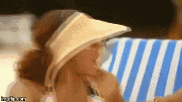 a woman wearing a visor and a bikini is laying on a striped towel .