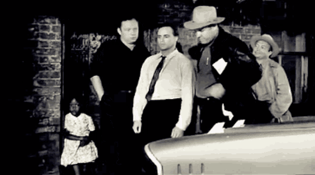 a black and white photo of a group of men and a girl