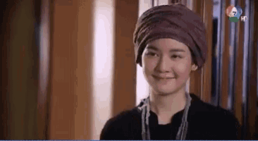 a woman wearing a purple turban is smiling and looking to the side