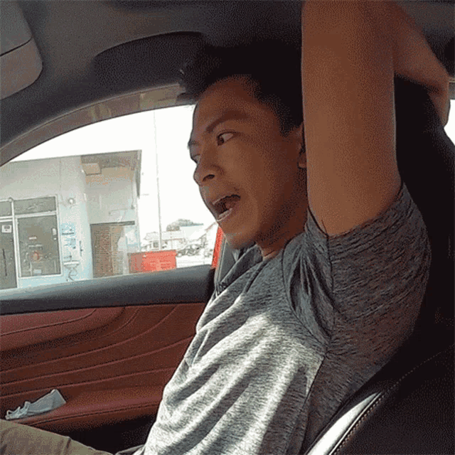 a man sitting in a car with his arms outstretched and his mouth open