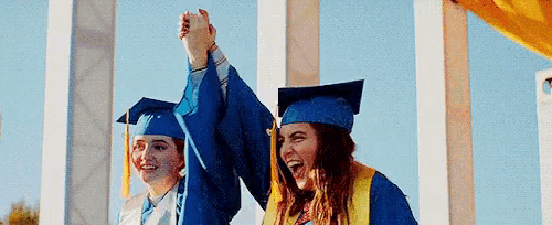 two female graduates are giving each other a high five