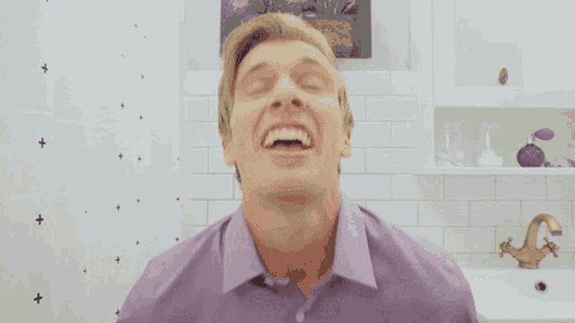 a man in a purple shirt has his mouth open in a bathroom