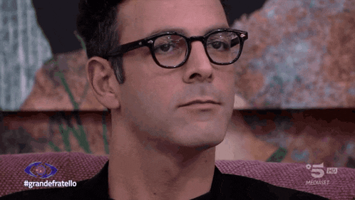 a man wearing glasses is sitting in front of a screen that says 5 hd