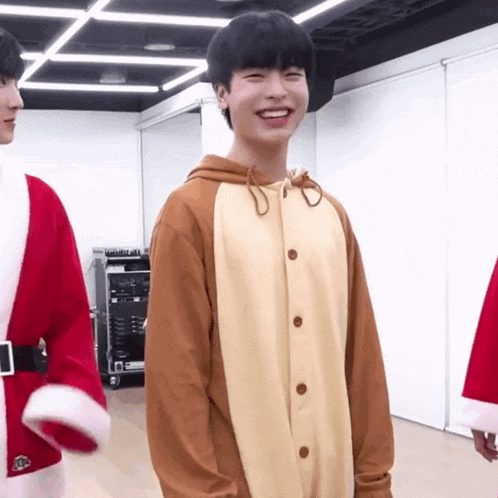 a young man in a reindeer costume is smiling in a room