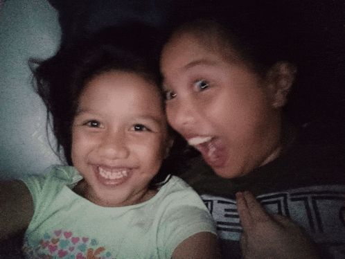 two little girls are posing for a picture and one of them is wearing a shirt that has the letter l on it