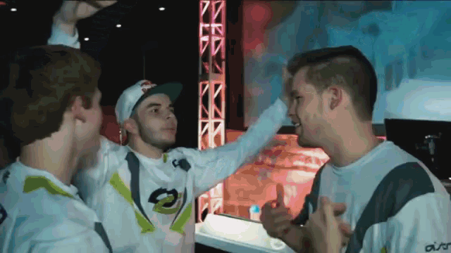 a man wearing a hat that says red bull on it is being congratulated by two other men